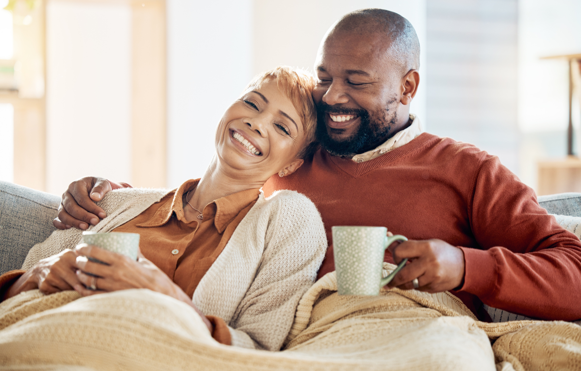 A couple laughing together while drinking coffee.