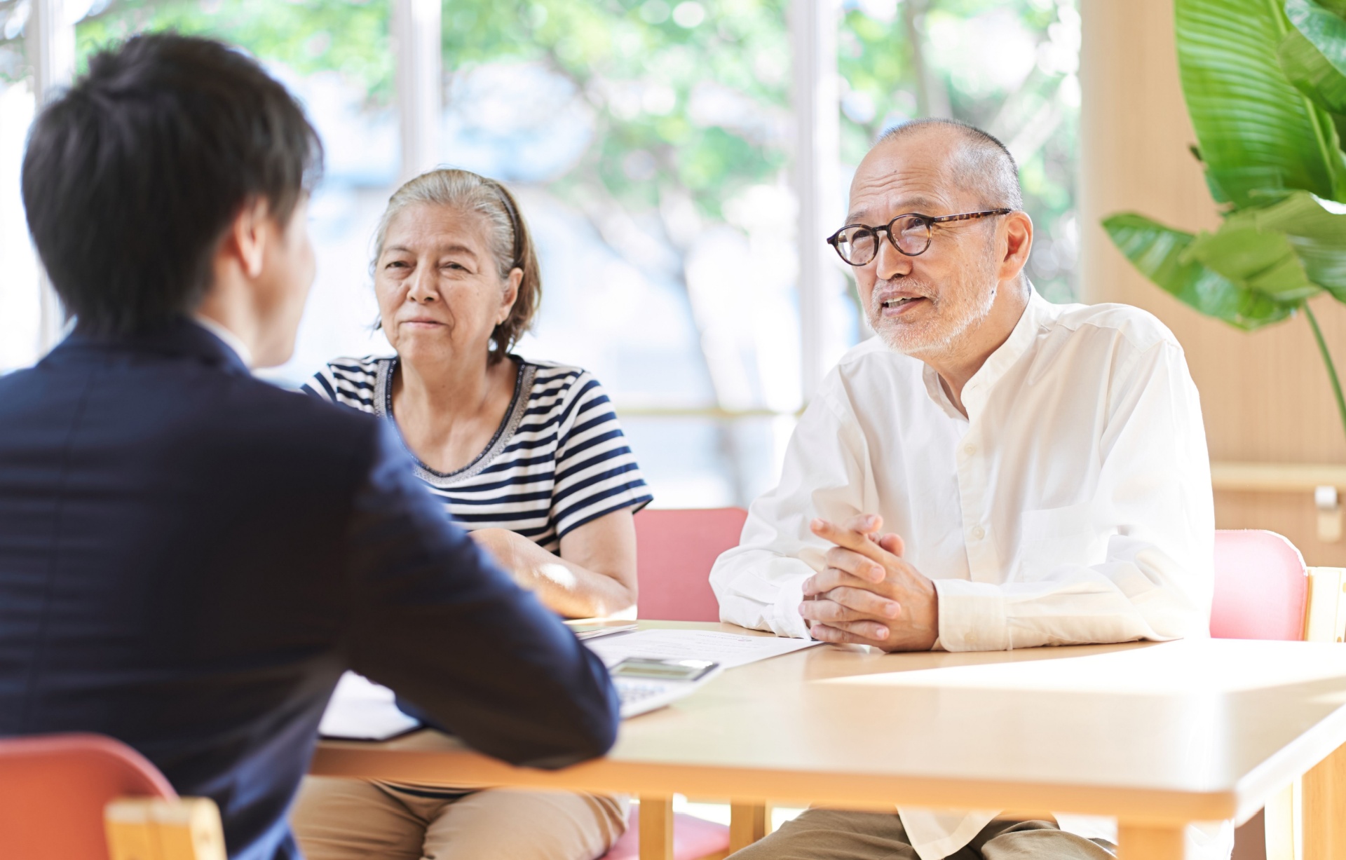 An older couple sits across a table from a younger man.