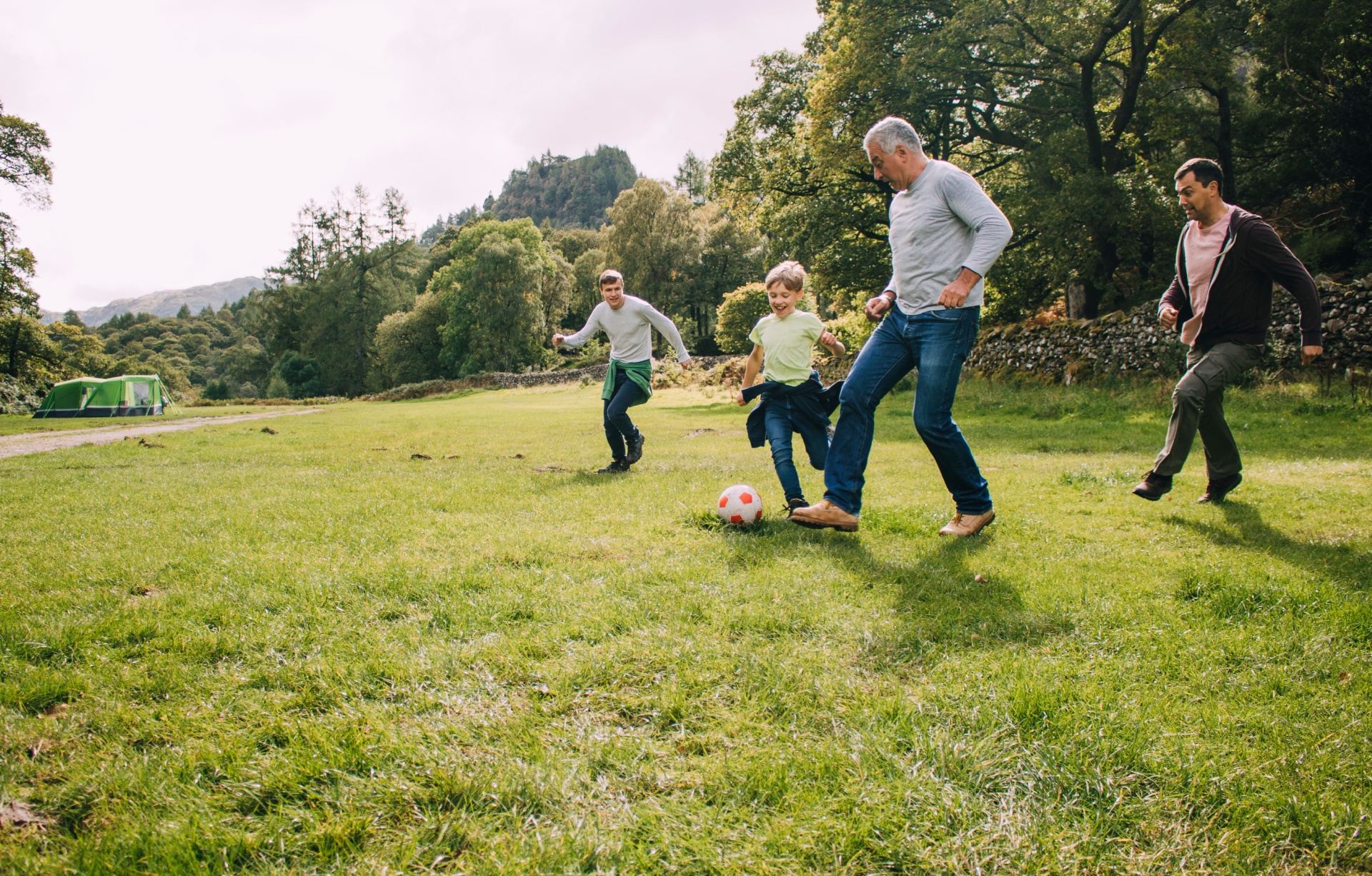 Multi-generational family playing football in a park.