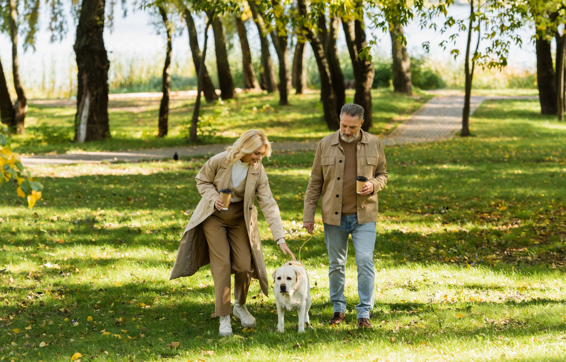 A couple and a dog walking in a park.