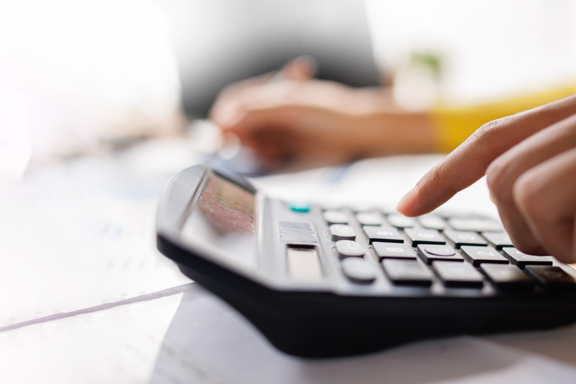 A person using a calculator while reviewing paperwork.