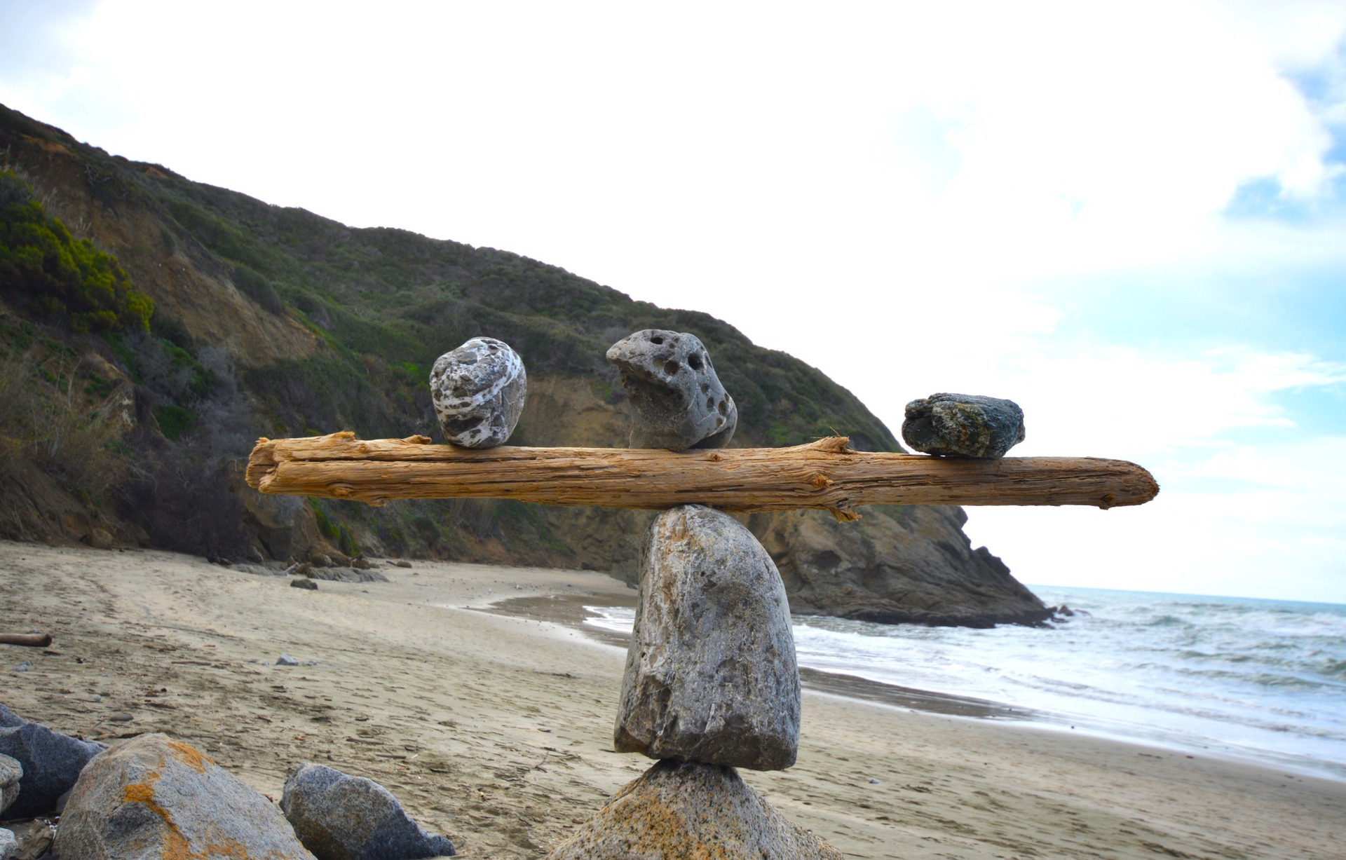 Rocks balancing on log on top of another rock